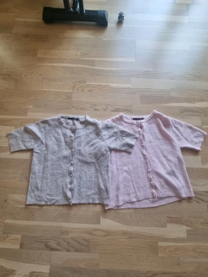 Tre kortärmade koftor med pärlknappar - Tre kortärmade koftor i mjukt stickat material, en i beigt, en I vit och en i ljusrosa. Den beiga och vita  är i strl xs kch den rosa är i s, men skulle säga att de är väldigt lika i storlek. Den beiga saknar en knapp som man ser på bilden två, men syns knappt. Går att köpa en om man vill skicka prisförslag isf. 1 kostar 70 kr styck från början men du kan skicka ett prisförslag. Vill bli av med dem.