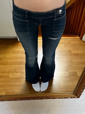 Marinblå lågmidjade jeans  - Marinblå lowwaist utsvängda jeans i storlek S från Gina tricot 14+. Modellen heter pleated flare jeans.