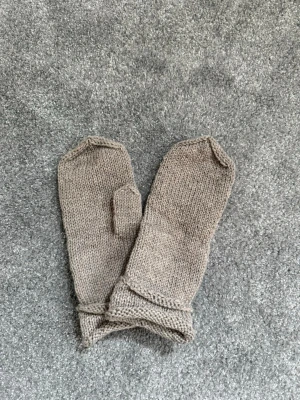 Beige stickade tumvantar i reflextråd - Beigea stickade tumvantar i enkel design med reflextråd integrerat i garnet. Perfekta för mörka och kalla dagar som ger en mysig känsla.✨ Passar dig som värderar säkerhet och gillar stilrena accessoarer!