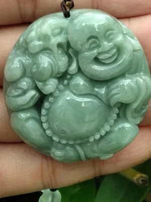 Grönt jadehalsband med snidat motiv - Unikt halsband med ett runt hänge i grön jade, snidat med ett detaljerat motiv. Hänget har en blank yta och hänger i ett mörkt snöre. Perfekt för dig som gillar naturmaterial och asiatiskt inspirerad design.