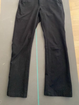 Svarta kostymbyxor - Säljer ett par svarta kostymbyxor med raka ben och låg midja. Materialet känns mjukt och följsamt. Passar dig som gillar enkel och stilren look.