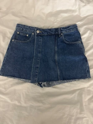 Blå jeansskorts - Säljer dessa blå jeansskorts från Gina. Ser ut som en kjol framifrån med omlott tyg. Nyskick och fin till sommaren. 