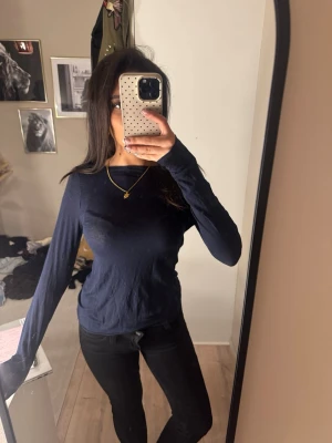 Intimissimi tröja - En enkel och stilren mörkblå långärmad topp med rund hals. Passformen är normal och materialet ser ut att vara mjukt och bekvämt, troligen bomull eller polyester. Perfekt att matcha med jeans eller kjol för en clean look. Däremot lite hål längst ner på framsidan som knappt syns. 