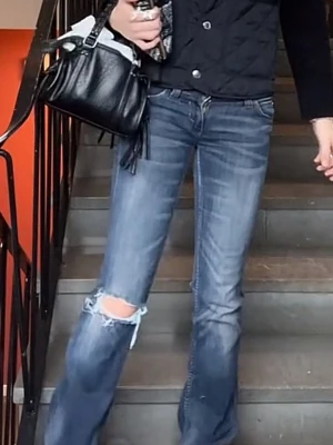 Cheap monday jeans - Säljer ett par blå bootcut jeans med slitningar och hål på ena knät. Jeansen har en klassisk femficksmodell och är tillverkade i denim med lätt tvättad look. Perfekta för en avslappnad och trendig stil.