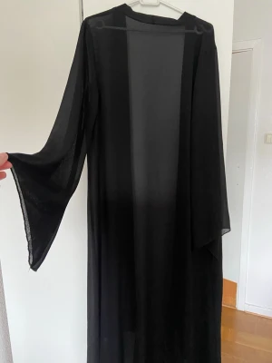 Svart transparent lång kimono - Säljer en svart, lång och transparent kimono/kofta. Materialet är tunt och lätt, perfekt för sommaren.