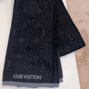 Svart halsduk från Louis Vuitton - Säljer en elegant svart halsduk från Louis Vuitton med deras ikoniska monogrammönster. Halsduken är perfekt för både höst och vinter och ger en lyxig touch till vilken outfit som helst. Den är i mycket bra skick och redo att användas direkt. Passa på att köpa denna stiliga accessoar! Inköpspriset är 4 950kr. Kvitto finns!
