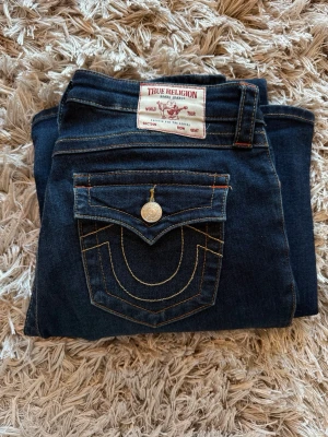 True Religion mörkblå bootcut jeans - Säljer true religion byxor! Extrem bra skick, har inte använt mer än 5 gånger. Säljer för att jag inte använder dem🩷Inga fläckar eller slitningar. Väldigt bra passform💋💋jag är 170cm och dem passar bra i längden samt midjan. Storlek w28