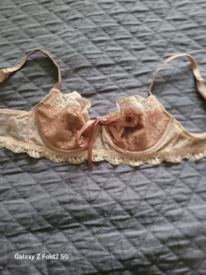 Intimissimi spets-bh - Söt bh i beige spets med dekorativ rosett framtill och juster soppar. Bh:n har genomskinliga spetsdetaljer och vacker kant i spets nedtill. catering till dig som gillar romantisk och feminin stil.