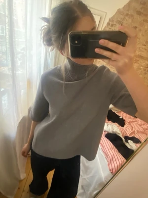 Grå polotröja med kort ärm - Snygg grå polotröja med korta ärmar och lös passform. Tröjan har en hög ribbad krage och är tillverkad i ett mjukt material som ger en stilren look. Perfekt för lager-på-lager och enkel att matcha med olika outfits💓