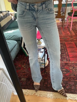 Ljusblå bootcut jeans låg midja  - Säljer ett par ljusblå jeans med bootcut passform och låg midja. Jeansen har klassiska fem fickor, bälteshällor och stängs med knapp och dragkedja. Materialet är denim i bomull och de har en snygg vintagekänsla. Perfekta till sneakers eller boots.