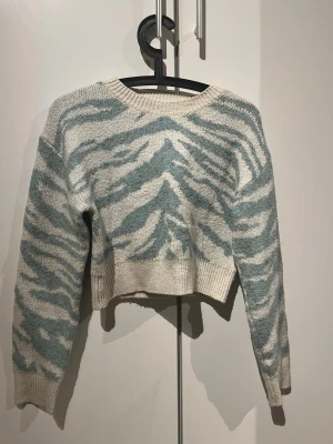 Zebramönstrad stickad tröja SHEIN - Trendig stickad tröja från SHEIN med zebramönster i ljusblått och vitt. Den är väl använd med i bra skick! Hör av er via intresse eller prisförslag!!!