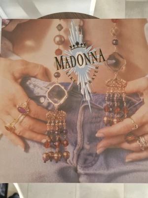 Madonna Like a Prayer vinyl - Säljer LP Madonna. Ett ikoniskt vinylomslag till albumet 'Like a Prayer' av Madonna. Omslaget har ett färgstarkt foto med smycken, jeans och Madonnas logga i metallic. Baksidan har låtlista och svartvit bild. Perfekt för samlare eller fans av popkultur. Inga repor.