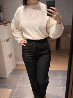 Vit stickad tröja med pärlor från H&M - Superfin vit stickad tröja från H&M med pärldetaljer över axlar och bröst. Rund halsringning och långa ärmar, mjukt material som känns skönt mot huden. Perfekt för dig som gillar att sticka ut med snygga detaljer.
