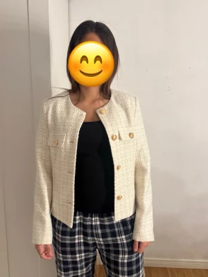 Krämvit tweedkavaj med guldknappar - Stilren krämvit kavaj i tweedmaterial med rund halsringning och fyra dekorativa guldknappar framtill. Två bröstfickor med lock och långa ärmar ger en klassisk look. Perfekt för dig som vill ha en elegant och trendig kavaj till din outfit. Aldrig kommit till användning+prislapp kvar!💗