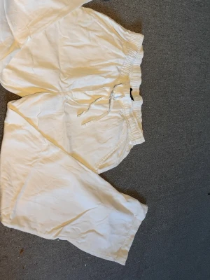 Vita linnebyxor från 157 - Säljer ett par vita linnebyxor från 157 med avslappnad passform och resår i midjan samt dragsko. Byxorna har sidofickor och är tillverkade i ett lätt och luftigt material, perfekt för varma dagar. Säljer då de inte passar längre, Skriv om ni har frågor 