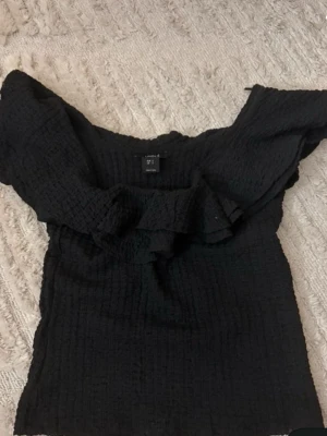 Svart offshoulder topp med volang - Säljer en svart offshoulder topp med volangdetaljer runt överdelen. Storlek xs 💕från Lindex 