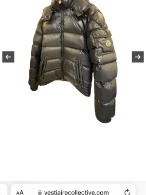 Svart pufferjacka från Moncler - Säljer en mörkgrön pufferjacka från Moncler med glansig finish och hög krage. Jackan har dragkedja framtill, två sidofickor och en ficka med Moncler-logga på ärmen. Klassisk boxig passform och vadderad design som håller dig varm under kalla dagar.