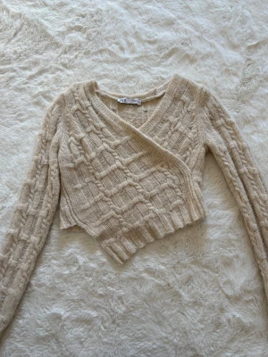 Beige omlottstickad tröja från ZARA - Säljer en jättefin beige stickad tröja från ZARA i storlek S. Aldrig använd så nyskick!