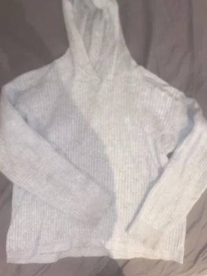 En grå tunn luvtröja - En grå ribbad tröja
