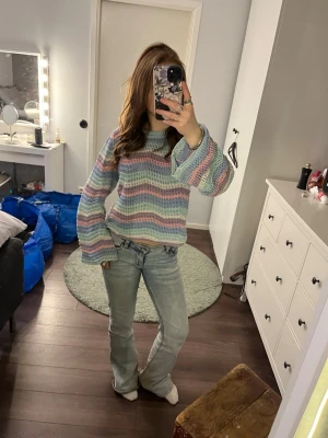 Pastellrandig stickad tröja - Säljer en stickad tröja med breda ärmar i pastellfärger som ljusblå, lila, rosa och mintgrön. Tröjan har ett vågigt randmönster och är lite croppad i modellen. Perfekt för dig som gillar färg och en avslappnad stil.