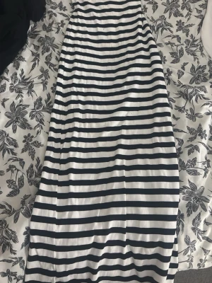 Randig långkjol i svart och vitt - Säljer en långkjol med svartvita horisontella ränder. Kjolen har en rak passform och är gjord i ett mjukt, stretchigt material som känns bekvämt mot huden. Perfekt för dig som gillar en enkel men stilren look.