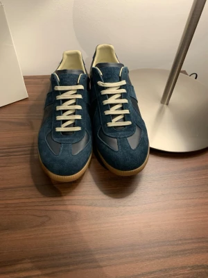 Maison margielas - Snygga mörkblå sneakers med ovandel i mocka och läder, vita snören och beige sula. Klassisk och stilren design som passar till det mesta. Insidan är ljus och skon har en låg profil för en clean look.