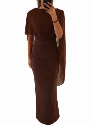 Bal klänning / Brun långklänning med capeärm - Snygg brun långklänning med unik capeärm på ena sidan och markerad midja. Klänningen har en elegant, figurnära passform och är gjord i ett tunt, flytande material som ger ett exklusivt intryck. Perfekt för dig som vill sticka ut med en stilren look.