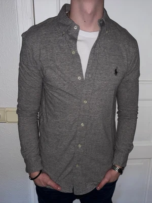 Grå skjorta från Ralph Lauren - Grå skjorta från Ralph Lauren i storlek S.  Fint skick till ett bra pris. Nypris: 1995kr. Mitt pris: 349kr. Vid frågor eller funderingar, tveka inte att höra av dig.