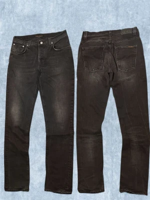 Svarta slim fit jeans från Nudie - Säljer ett par svarta slim fit jeans från Nudie med klassisk femficksdesign och snygga detaljer. Jeansen har en lätt tvättad look och raka ben. Perfekt för dig som gillar stilrena och bekväma jeans.
