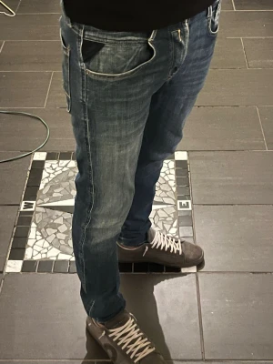 Blå slim fit replay jeans 28-30/32  - Säljer ett par blå slim fit replay jeans med snygga slitningar och ljusare tvätt. Klassisk femficksmodell med dragkedjegylf och kontrastsömmar. Perfekta för en avslappnad och trendig look. Elastiska som ger en den bästa passningen någonsin och midjan funkar upp mot storlek 30 för att de är elastiskt