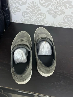 Gråa sneakers i mocka - Snygga gråa sneakers i mocka med klassisk låg profil och vita sulor. Skorna har en stilren design med matchande grå skosnören och diskreta sömmar. Perfekta för dig som gillar en clean och enkel look. Den är lite stor i storlek så passar 43 också 