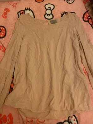 Beige långärmad blus Vero Moda - Snygg beige blus från Vero Moda med rund halsringning och långa ärmar. Blusen har en enkel och avslappnad passform, perfekt att styla med jeans eller kjol. Tillverkad i ett lätt och mjukt tyg som känns skönt mot huden.