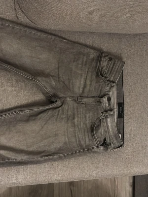 Grå jeans från Replay -  Jag säljer ett par snygga grå jeans från Replay flr att jag har vuxit ur de. Byxorna är i perfekt skick och de har inte slitningar eller trasiga delar. Byxorna är i relaxed from så de är inte för baggy men ändå inte för skinny. Längden är 150 cm men de är egentligen lite större. Hör av dig för mer info!