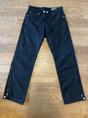 HOPE Svarta Chinosbyxor - Svarta byxor i chinosmaterial från HOPE, med dragkedja längst ner på benen. Storlek 44. Sparsamt använda, i jättefint skick. Säljs pga minskad användning. Bara att höra av dig vid intresse, frågor eller önskan om fler bilder! Mvh