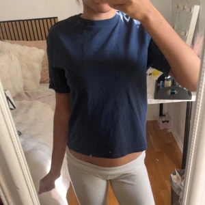 Mörkblå t-shirt från Gina Tricot - En enkel och stilren mörkblå t-shirt från Gina Tricot. T-shirten har korta ärmar, rund halsringning och en normal passform. Perfekt basplagg att matcha med allt. Tillverkad i mjuk bomull för skön känsla.