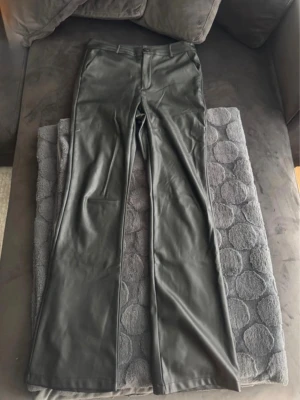 Skinnbyxor - Utsvängda skinnbyxor (PU material) , strl L Inuti är det lite fleece liknande material   Använda max 2-3 ggr, tyvärr ett litet hål i byxorna (se bild)