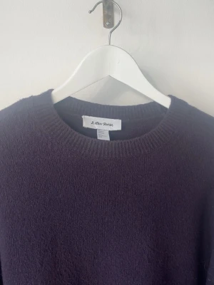 Mörkblå stickad tröja & Other Stories - Mysig mörkblå stickad tröja från & Other Stories med rund halsringning och långa ärmar. Tröjan har en enkel, klassisk design med ribbade muddar vid ärmslut och nederkant. Perfekt för lager på lager under kyliga dagar.