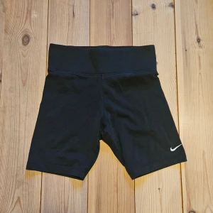 Svarta cykelshorts från Nike - Säljer ett par svarta cykelshorts från Nike med hög midja och diskret logga på vänster ben. Shortsen är tillverkade i stretchigt material. Storlek M, men sitter bra på mig som har S.