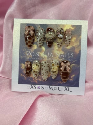 SweetLeo (S);Medium Almond - Unika handgjorda press-on naglar i brun och beige med leopardmönster, 3D-rosetter och guldfärgade detaljer. Mix av sanrio charms, handgjorda och riktigt trendiga. Perfekt för dig som vill sticka ut med coola detaljer och djurmönster.S: 15 mm, 11,5 mm, 12 mm, 11 mm, 9 mm 