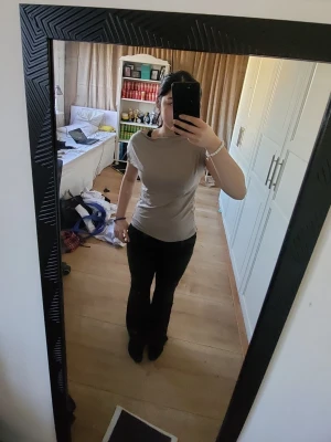 Beige kortärmad topp - En enkel och stilren beige topp med korta ärmar och rund hals. Toppen har en slim passform och är tillverkad i mjukt bomullsmaterial, perfekt för en clean och avslappnad look.