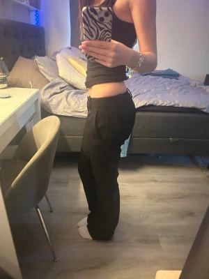 Svarta raka kostymbyxor - Säljer ett par svarta kostymbyxor med rak passform och låg midja. Byxorna har pressveck framtill och sidofickor för en clean look. Byxorna är uppsprätta längst ner vilket ger några extra centimeter till byxan.