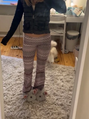 Mönster byxor  - Säljer ett par mjuka och stretchiga mjukisbyxor med lila, rosa och vita zigzag-ränder. Byxorna har utsvängda ben och bred resår i midjan för extra komfort. Perfekta för chill dagar hemma eller när du vill ha en avslappnad stil.