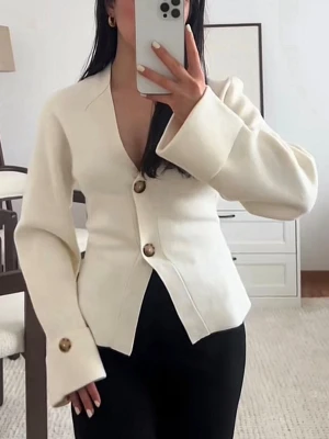 Vit figursydd kofta med stora knappar - Trendig vit kofta med figurnära passform och stora bruna knappar framtill. Koftan har djup V-ringning, vida ärmar med breda muddar och en stilren, minimalistisk look. Perfekt för dig som gillar en clean och modern stil.