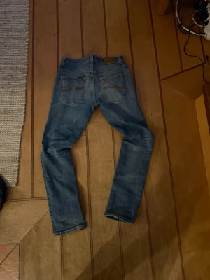 Nudie jeans  - Snygga blå skinny jeans från nudie med klassisk femficksdesign och slitna detaljer på låren. Jeansen har normal midja och smal passform hela vägen ner. Perfekta till en avslappnad stil och tillverkade i mjukt denimtyg. W31 L32