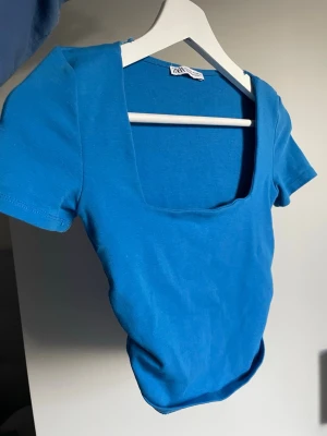 Blå topp - Fin blå croppad topp med fyrkantig urringning från Zara som knappt använts. Bra skick.