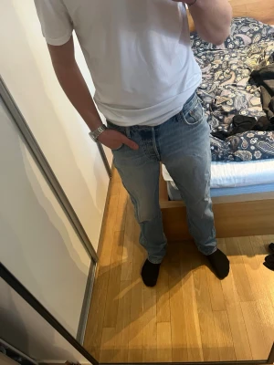 Levi's 501 - Säljer ett par klassiska ljusblå jeans från Levi's med rak passform och fem fickor. Jeansen har en snygg vintagekänsla och är tillverkade i slitstark denim. Perfekta till en avslappnad stil och passar till det mesta i garderoben. Lite skav vid foten men inget som märks. Hör av er vid mer frågor 