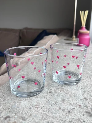 Handmålade glas med rosa hjärtan - Säljer ett par handmålade glas med rosa hjärtan 💕 Glasen är från IKEA och är i mycket gott skick. Tål mild maskindisk. Måtten är 7,5x7,5cm