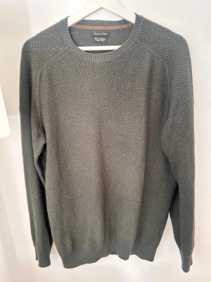 Svart/grön stickad tröja Massimo Dutti - Snygg grå stickad tröja från Massimo Dutti med rund halsringning och diskret strukturmönster. Tröjan har långa ärmar och ribbade muddar vid ärmslut och nederkant. Perfekt för lager på lager och enkel att matcha.
