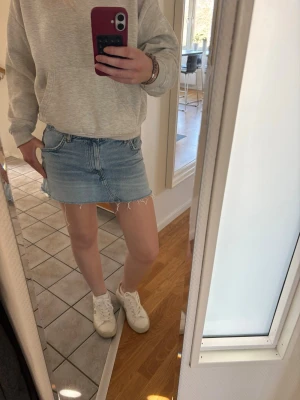 Ljusblå jeanskjol - Trendig ljusblå jeanskjol i kort modell, fransig kant nertill. Klassisk femficksdesign och normal passform. Perfekt för dig som gillar en avslappnad och cool stil.