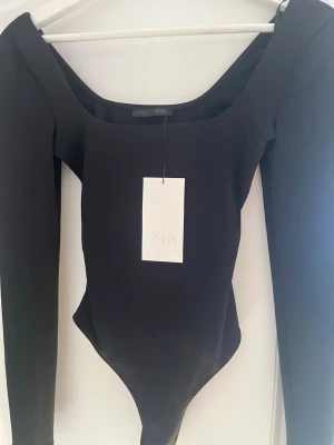Svart långärmad body från Zara - Svart body från Zara med långa ärmar och rundad urringning. Tillverkad i ett stretchigt material, aldrig använd🙌🏻🥰 tar emot prisförslag!!